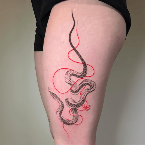 Xăm hình rắn chỉ đỏ, fine linework tattoo, xăm đùi đẹp, minimalist art tattoo: Rắn mảnh đan cùng sợi chỉ đỏ mềm, nhẹ nhàng nhưng gây nhớ.