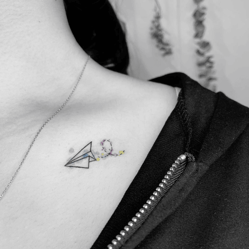 Xăm hình máy bay giấy mini cho nữ ở vai - Biểu tượng của tuổi thơ trong trắng và những ước mơ bay cao bay xa không giới hạn.