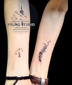Hình xăm lông vũ mini và cân công lý ở cổ tay